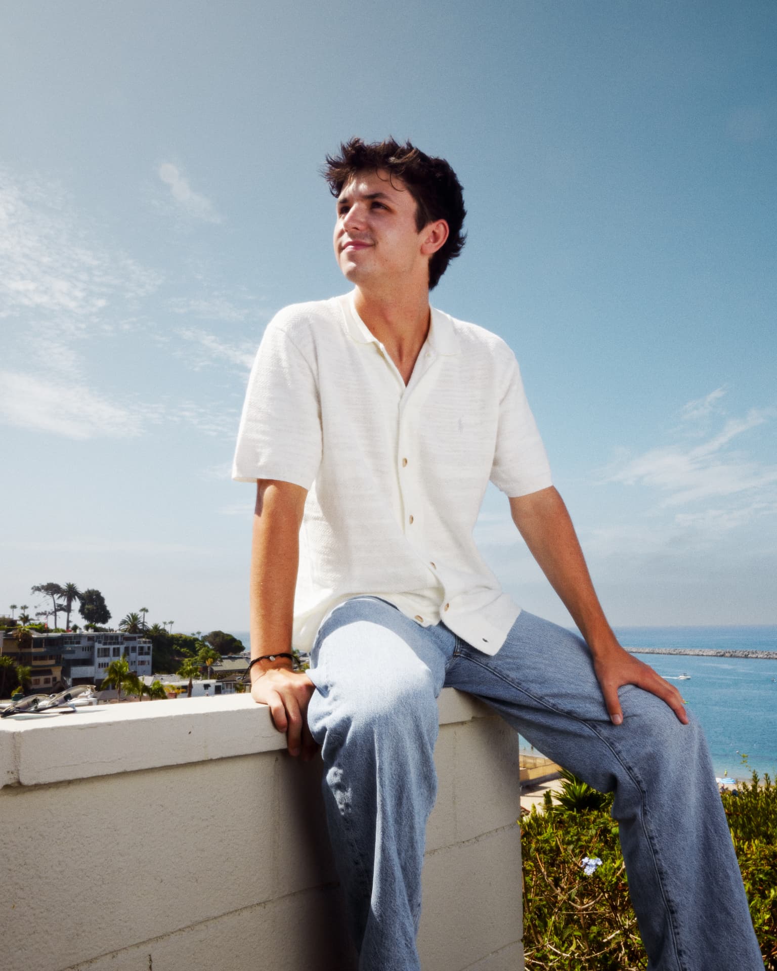 James Brewster sitting on a rooftop wall above the California coast